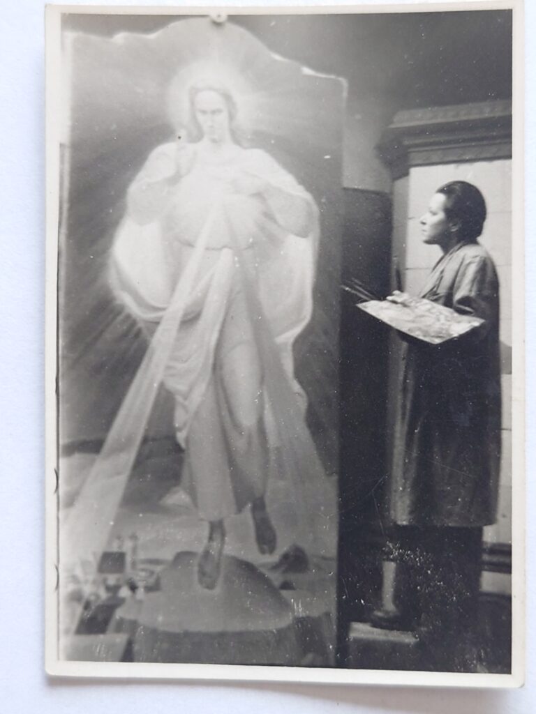 artysta z paletą stoi przed dużym obrazem